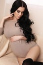 Pregnant woman with long dark hair wears elegant cardigan Royalty Free Stock Photo