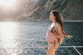 Pregnant woman with long hair in swimsuit on yacht