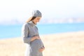 Pregnant woman looking at belly on the beach in winter Royalty Free Stock Photo