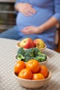 Pregnant Woman Looking At Bowls Of Healthy Fruit And Vegetables Royalty Free Stock Photo