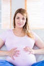 Pregnant woman looking at camera with hands on belly Royalty Free Stock Photo