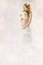 Pregnant woman looking at flowers in white dress. Royalty Free Stock Photo