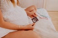 Pregnant woman looking at her baby twins sonography. Happy expectant lady enjoying first photo of her kids, face is unrecognizable Royalty Free Stock Photo