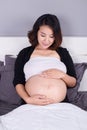 Pregnant woman looking at her belly while lying on bed Royalty Free Stock Photo