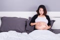 Pregnant woman looking at her belly while lying on bed Royalty Free Stock Photo