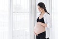 Pregnant woman looking her belly with window background Royalty Free Stock Photo