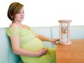 Pregnant woman looking on the hourglass Royalty Free Stock Photo