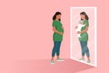 Pregnant woman looking in a mirror and seeing herself with her baby Royalty Free Stock Photo