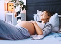 Pregnant woman looking at ultrasound image relaxing in bed at home. Expectant mother waiting and preparing for baby