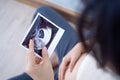 A pregnant woman is looking at an ultrasound photo of fetus. Mother gently touches the baby on stomach.Women are pregnant for 2-3 Royalty Free Stock Photo