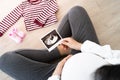 A pregnant woman is looking at an ultrasound photo of fetus. Mother gently touches the baby Royalty Free Stock Photo