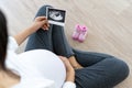 A pregnant woman is looking at an ultrasound photo of fetus. Mother gently touches the baby on stomach.Women are pregnant for 30 w Royalty Free Stock Photo