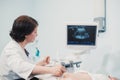 Pregnant woman looking at ultrasound shots of her growing baby showed by her doctor during medical examination Royalty Free Stock Photo