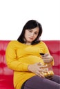 Pregnant woman looks bored while watch television Royalty Free Stock Photo