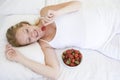 Pregnant woman lying in bed with bowl of fruit Royalty Free Stock Photo