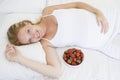 Pregnant woman lying in bed with bowl of fruit Royalty Free Stock Photo