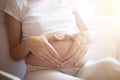 Pregnant woman lying in bed and touch her belly. Pregnancy heart shape at home, love sign Royalty Free Stock Photo