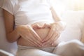 Pregnant woman lying in bed and touch her belly. Pregnancy heart shape at home, love sign Royalty Free Stock Photo