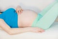 Pregnant woman lying on couch touching her belly Royalty Free Stock Photo