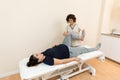 A pregnant woman lying on a massage table while a physiotherapist massages her legs at a health center Royalty Free Stock Photo