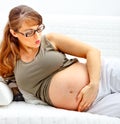 Pregnant woman lying on sofa and holding belly Royalty Free Stock Photo