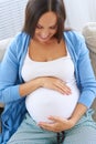 Pregnant woman lying on sofa holding hands on belly Royalty Free Stock Photo