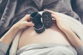 Pregnant woman lying on the sofa and holding shoes unborn child. Royalty Free Stock Photo