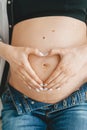 Pregnant woman make Heart-shaped hand on belly. Love sign. Closeup Royalty Free Stock Photo