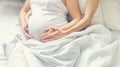 Pregnant woman with man hug belly in bed. Selective focus Royalty Free Stock Photo