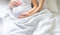 Pregnant woman with man hug belly in bed. Selective focus Royalty Free Stock Photo