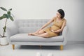 Pregnant woman massaging a swollen foot. Swelling in pregnancy. Swollen legs. Pregnant woman sitting on the sofa Royalty Free Stock Photo