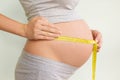 Pregnant woman measures her stomach. Pregnancy and weight gain. Pregnancy and sport. Big belly. Trimester Royalty Free Stock Photo