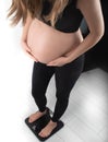 Pregnant woman measures her weight gain in pregnancy on weight scale Royalty Free Stock Photo