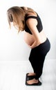 Pregnant woman measures her weight gain in pregnancy on weight scale Royalty Free Stock Photo