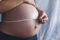 A pregnant woman measuring her belly with a tape
