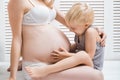 Pregnant woman mother and baby son are hugging. Cute boy touching mom`s belly Royalty Free Stock Photo