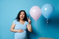 Pregnant woman mother caressing belly, showing two fingers, expressing amazement at gender reveal party. Expecting twins Royalty Free Stock Photo