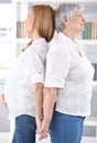 Pregnant woman and mother standing back-to-back