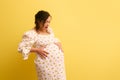 Pregnant woman, mother to-be holds belly, cries and shouts, isolated on yellow. Easy delivery, pregnancy and parturition Royalty Free Stock Photo