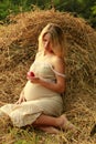 Pregnant woman on nature near the haystacks