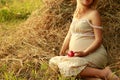 Pregnant woman on nature near the haystacks