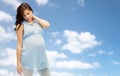 Pregnant woman with neckache over blue sky