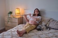 A pregnant woman next to her pet on a home bed reads a book in the light of an evening lamp Royalty Free Stock Photo