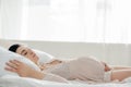 Pregnant woman in nightie touching tummy while sleeping in bed Royalty Free Stock Photo