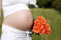 Pregnant woman outdoor with orange tulips in her hands Royalty Free Stock Photo