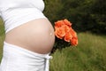 Pregnant woman outdoor with orange tulips in her hands Royalty Free Stock Photo