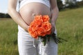 Pregnant woman outdoor with orange tulips in her hands Royalty Free Stock Photo