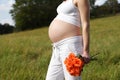 Pregnant woman outdoor with orange tulips in her hands Royalty Free Stock Photo