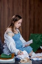 Pregnant woman is packing baby clothes for going to maternity hospital. Woman taking notes. Royalty Free Stock Photo