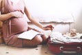 Pregnant woman packing bag for maternity hospital, making notes, checking list in diary. Expectant mother with suitcase of baby Royalty Free Stock Photo